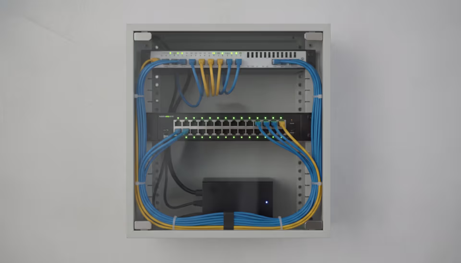 Organized home network rack with patch panel and ethernet cables connected to a network switch with green LED indicators
